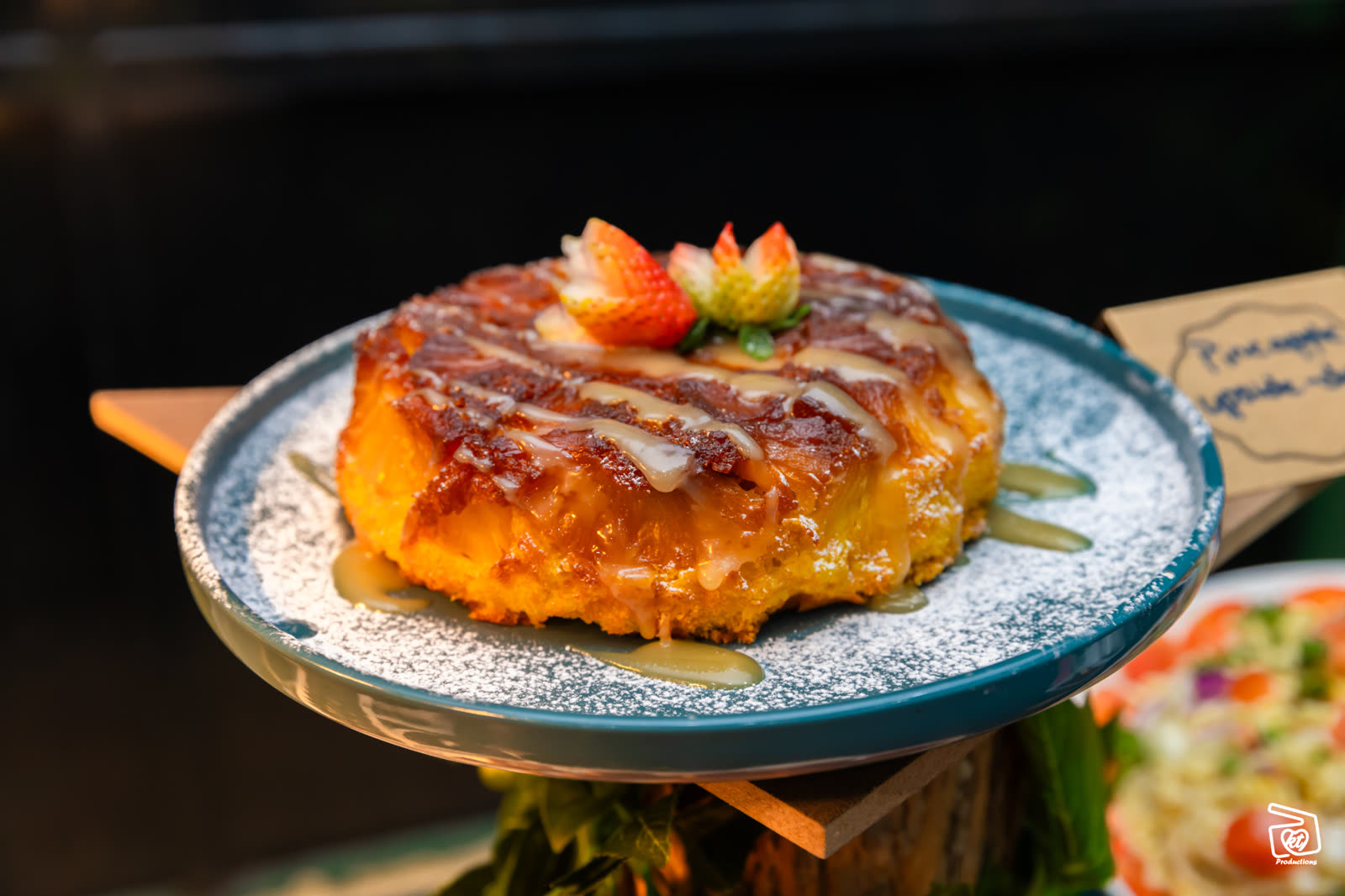 Pineapple upside-down cake plated with strawberries and caramel drizzle