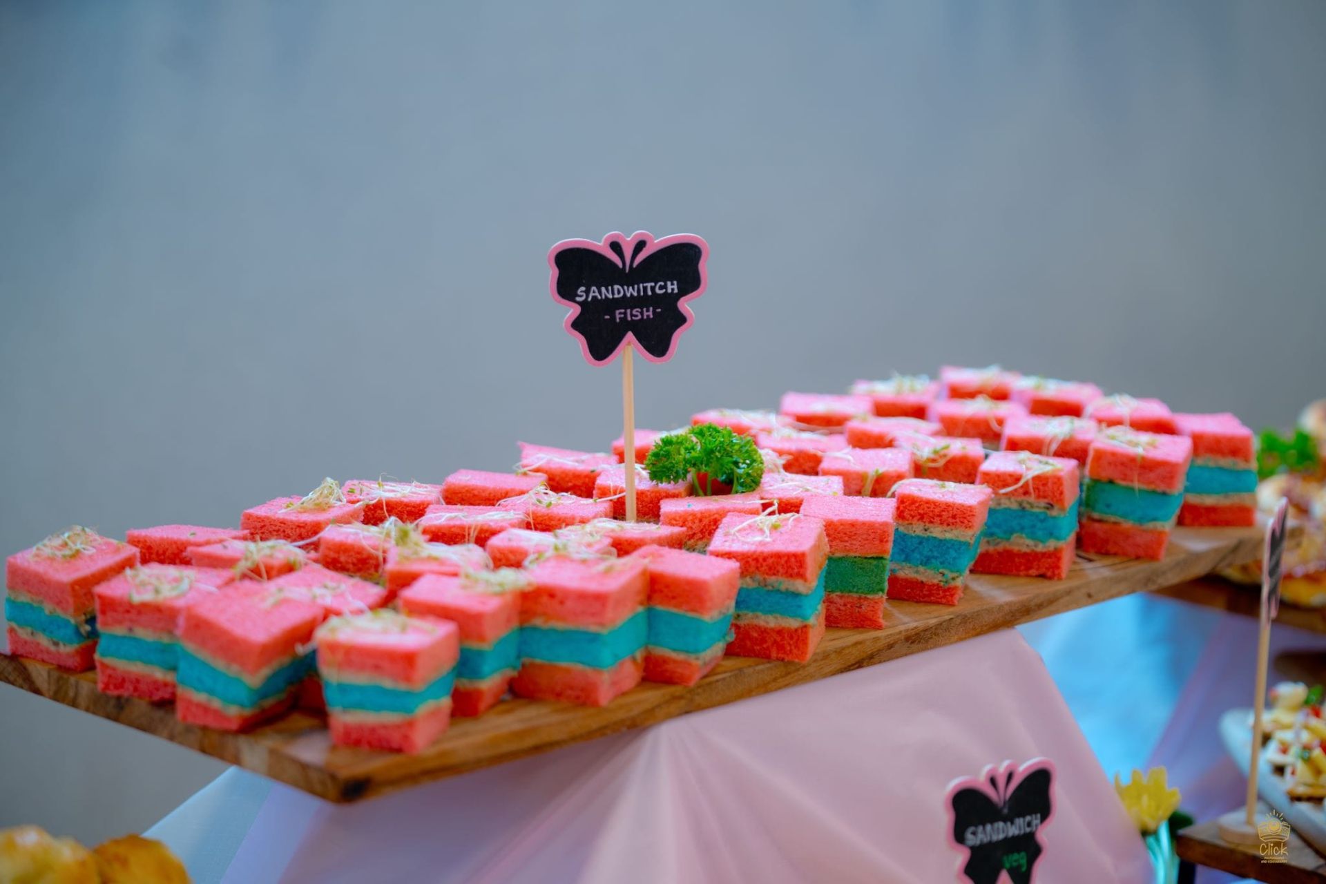 Colourful layered high tea sandwiches on a wooden board